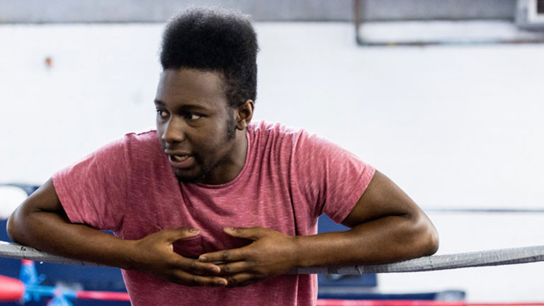 Ben rests against the ropes of a wrestling ring.