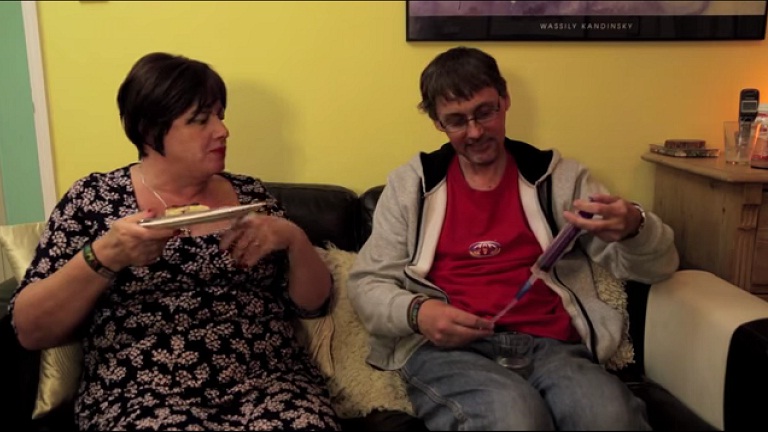 Jayne and Paul sitting on the sofa eating dinner