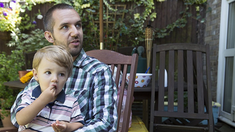 Luke holds his son in the garden 