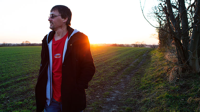 Paul on a walk in a field with the sun setting in the background