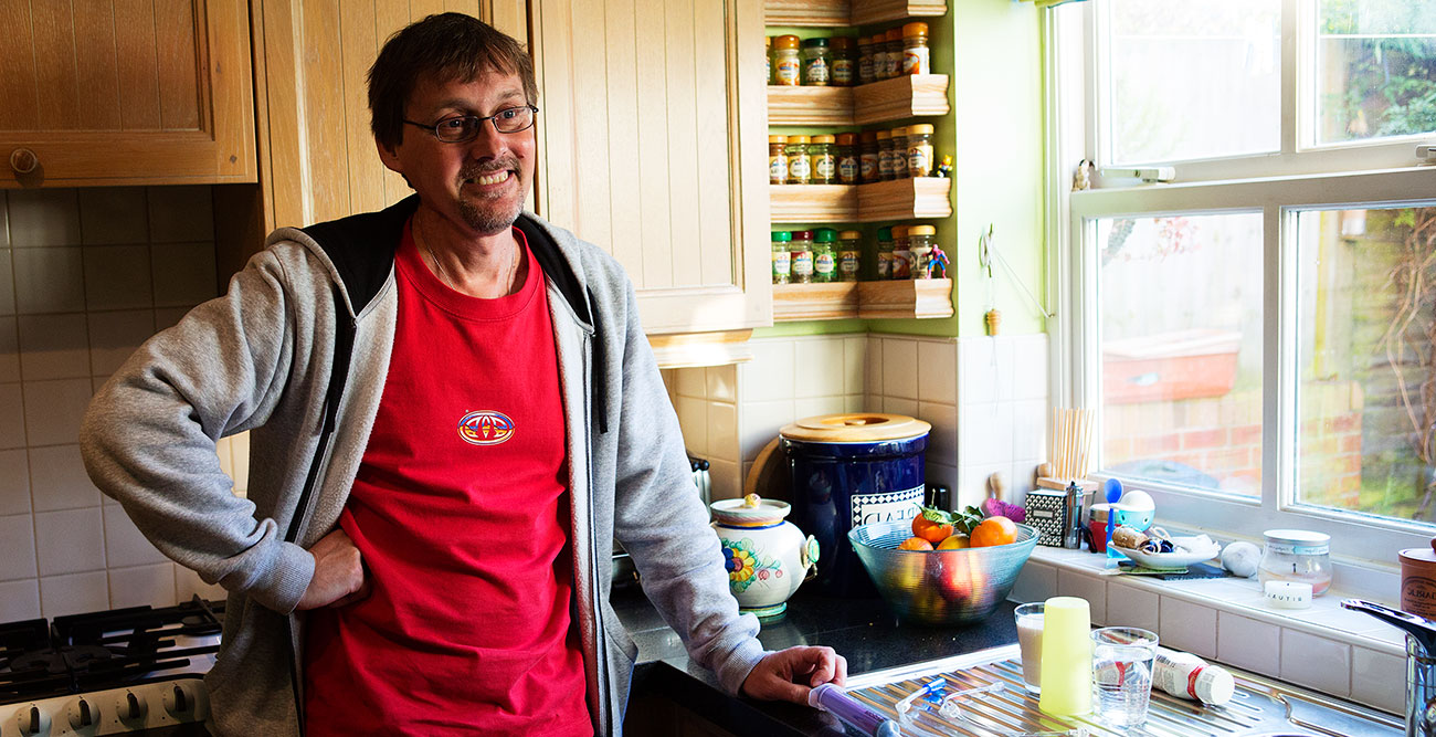 Paul stands by the window in his kitchen smiling