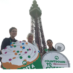 Supporters standing in front of Blackpool Tower holding cake shaped placards.