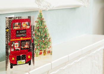A christmas card on a mantlepiece, with a bed London bus on it.