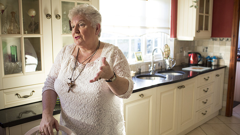 Philomena stands in her kitchen