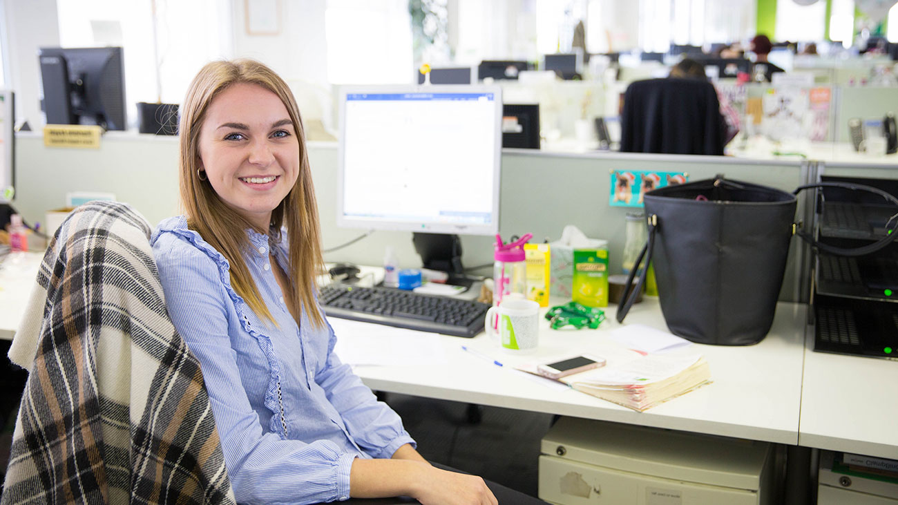 A Macmillan intern sits at a desk in an office.