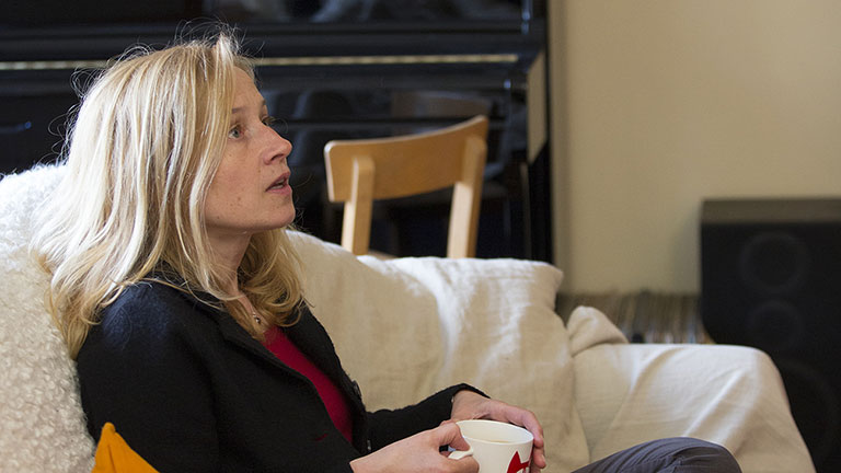 Lara sits on her sofa gazing upwards