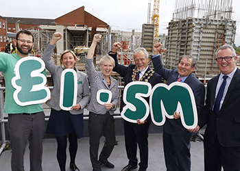 Six people, smiling and throwing their fists triumphantly into the air, holding a sign saying '£1.5 m'.
