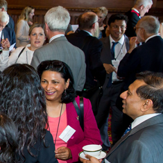 Members and officers standing, talking together in a parliamentary meeting room.