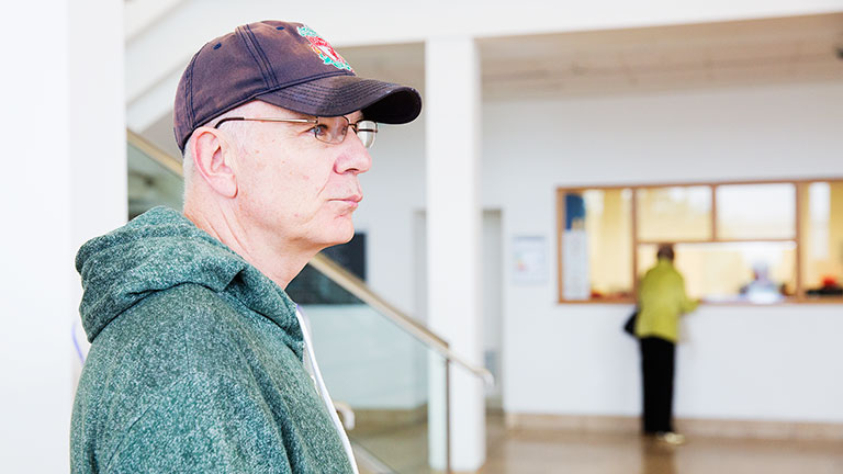 Gary in hospital wearing his baseball cap and glasses