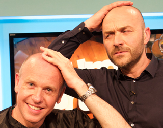 Two bald men touching their heads.