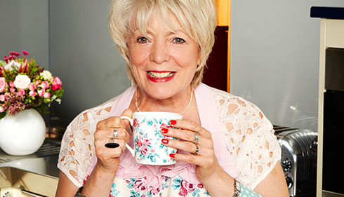 Celebrity Alison Steadman smiles holding a mug.