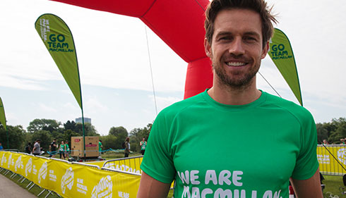 Celebrity Andrew Cooper smiles at a Macmillan outdoor event.