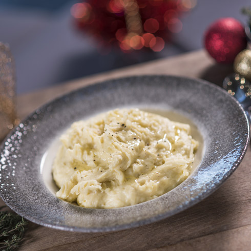 Creamy mash potato on a grey plate surrounded by Christmas decorations.