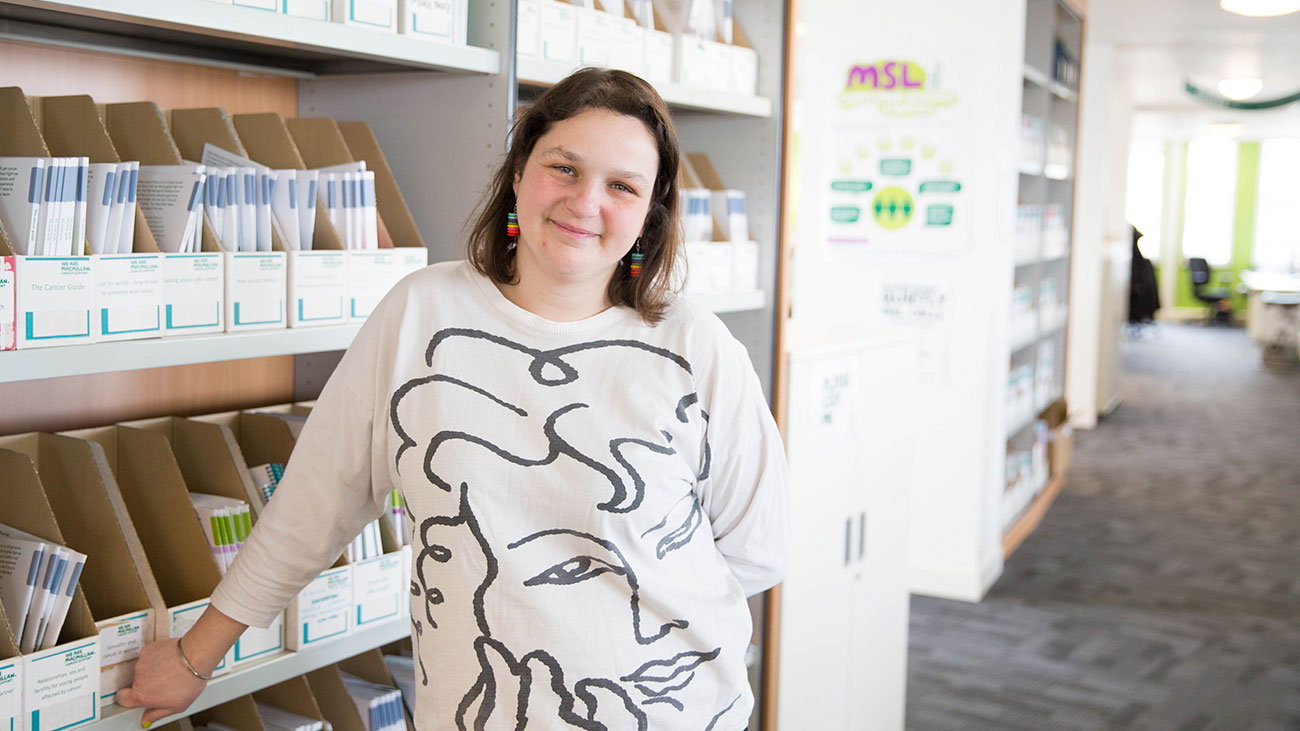 A female Macmillan intern manager stands in an office smiling.