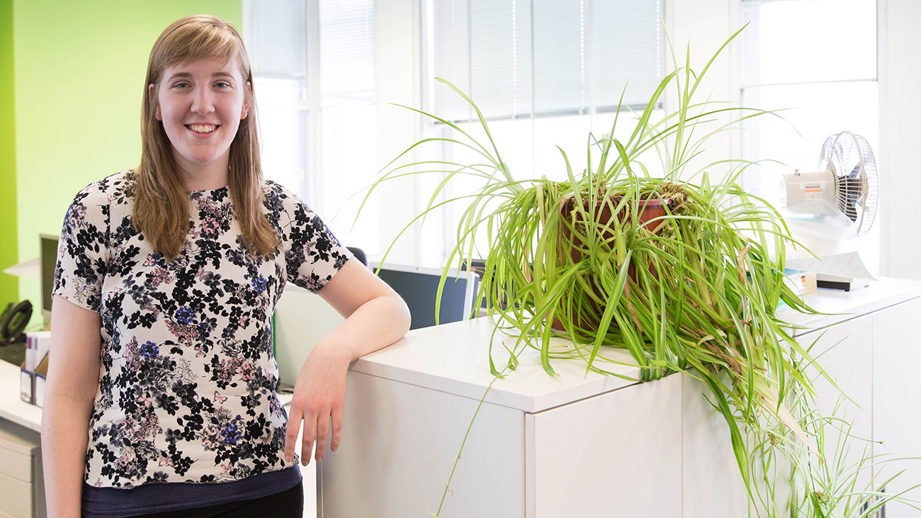A female Macmillan intern manager stands in an office smiling.