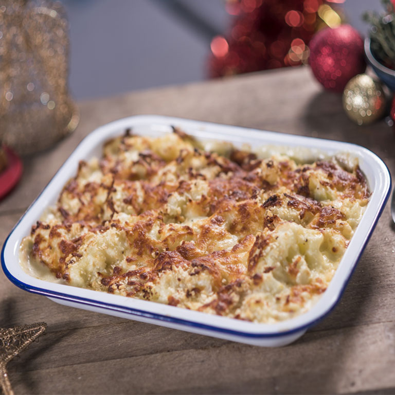A creamy leek and cauliflower bake surrounded by Christmas decorations. 