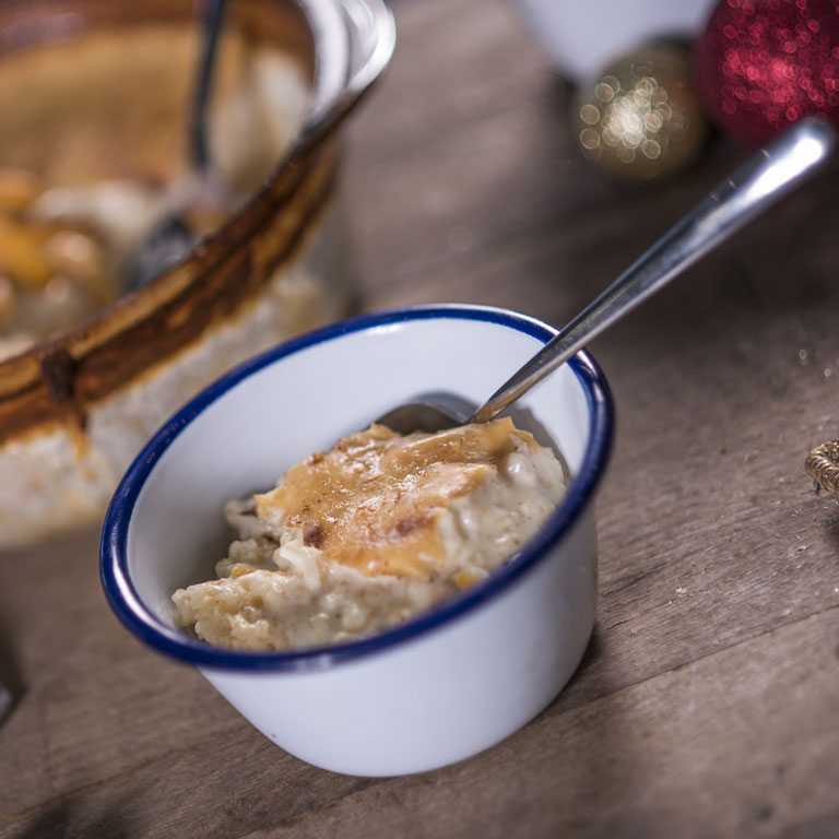 Rice pudding in a bowl surrounded by Christmas decorations.