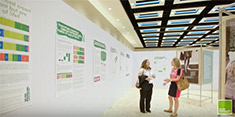 Two women stand talking in an exhibition room with large research posters on the walls.