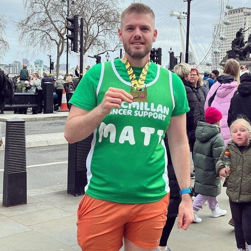 Matt, a white male in running shorts and t shirt with a running medal.