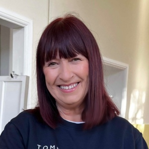 A selfie of Julie that shows her from the shoulders up. She is looking at the camera and smiling.