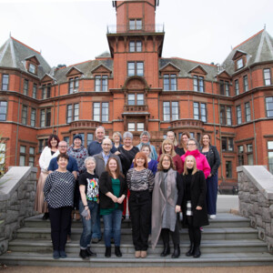 The Northern Ireland Cancer Experience group are outside standing on steps leading to a building. 