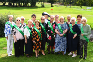 The Merythyr Tydfil Fundraising Committee are standing outside on a golf course. They are looking at the camera and smiling.