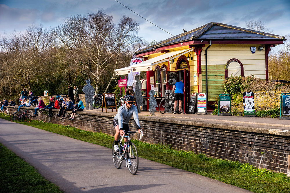 A man cycling past a cafe on the Bristol-Bath bike trail