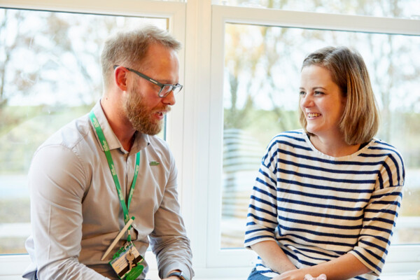 A Macmillan nurse and his patient are talking and smiling together