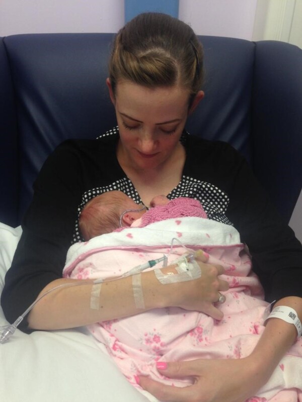 A woman is holding her baby while she is having chemotherapy. 