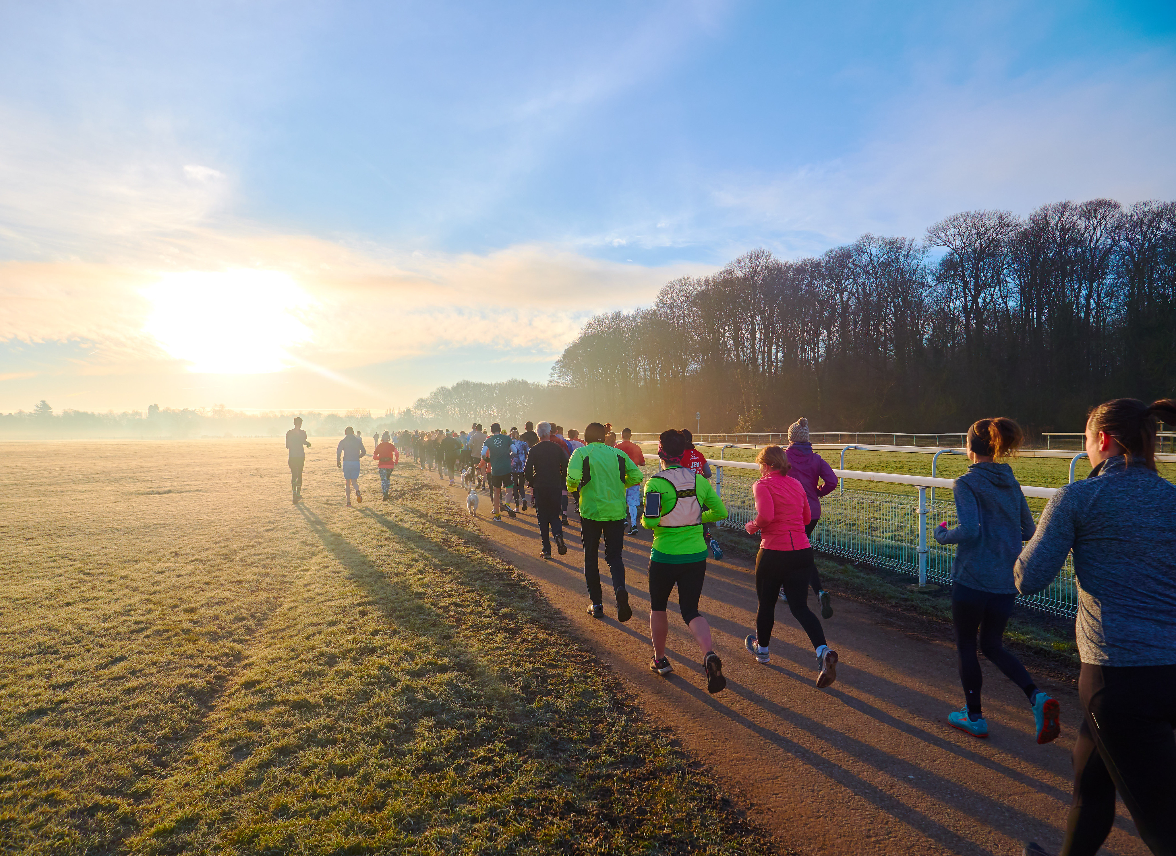 People running next to a horse racing track