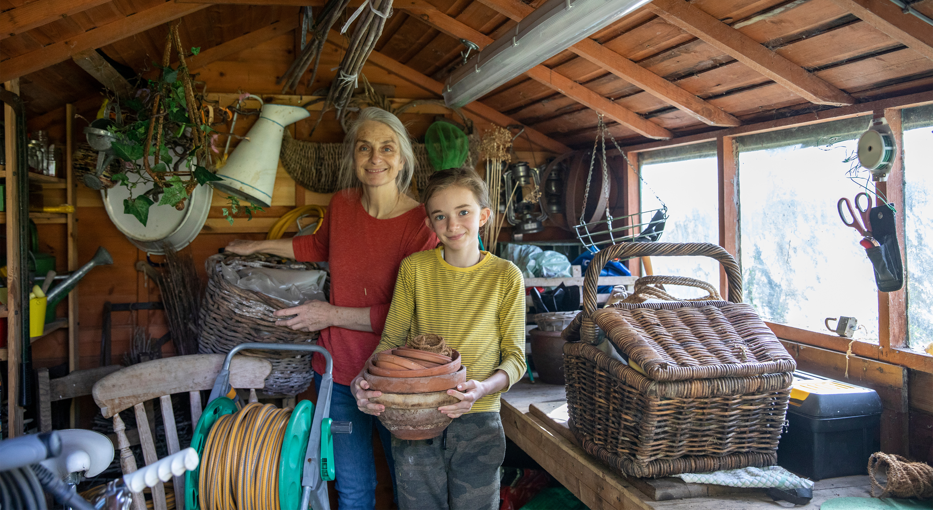 Two people clear out clutter from a garden shed for good causes.