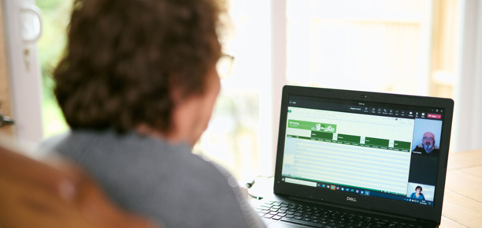 A woman sits at a desk with her laptop on a video call.