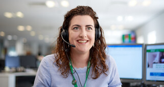 A woman wearing a headset working on the Macmillan Support Line