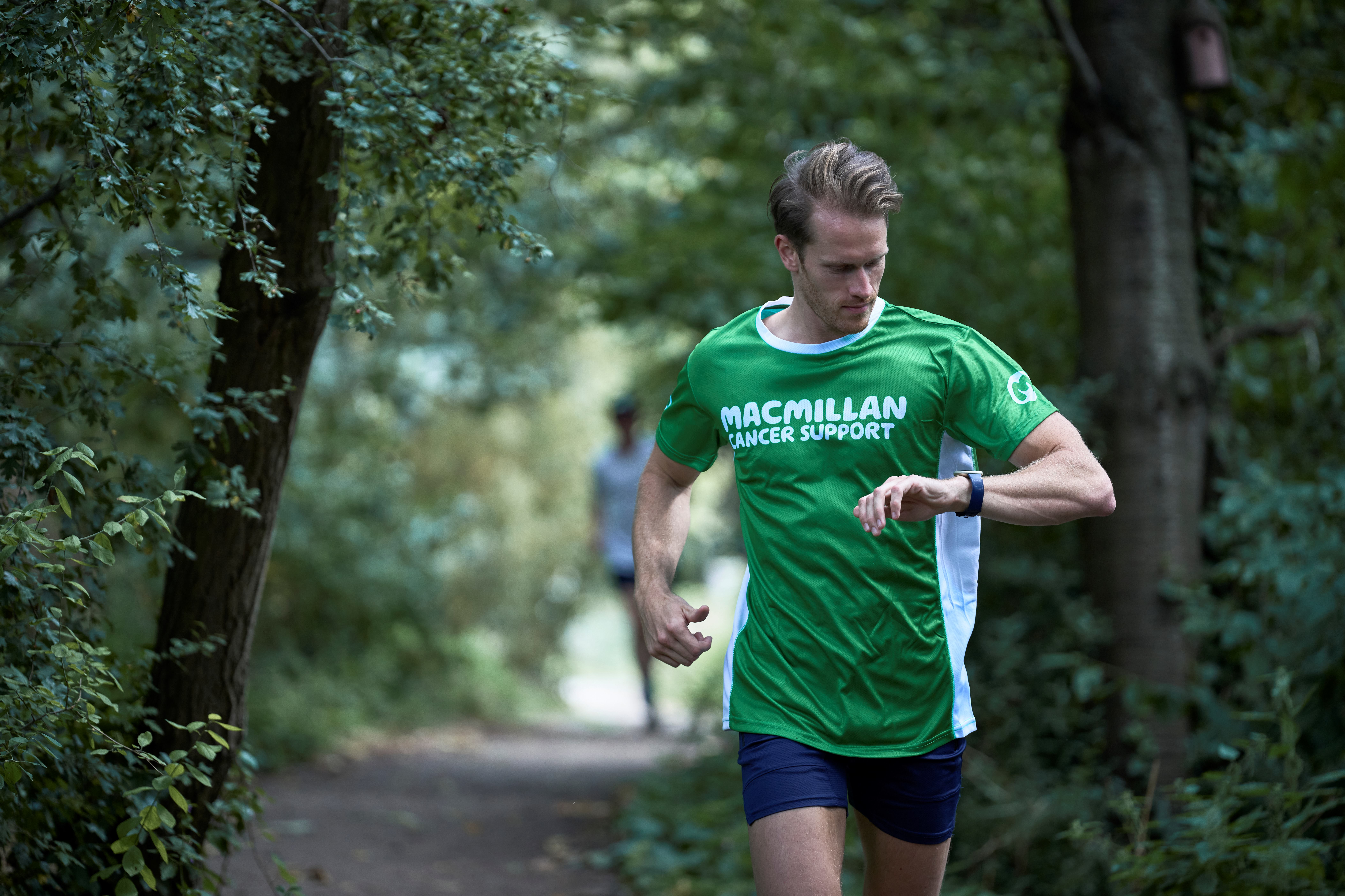 Man running in a green Macmillan t-shirt checking his watch