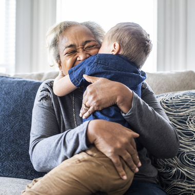 An older woman giving her grandson a big hug while sitting on a couch
