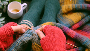 Person in fingerless gloves knitting