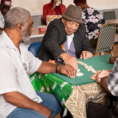 Older men sitting around a table playing dominoes together