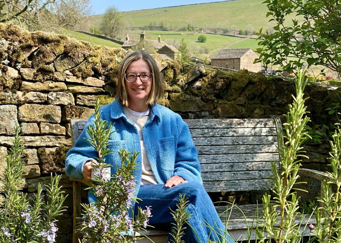 Maggie sitting on a bench in her garden.