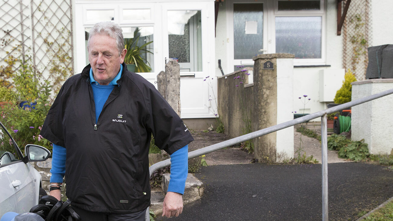 Dave carries his golf clubs to his car. 