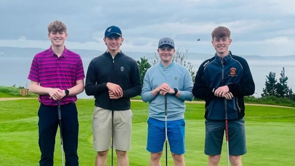 A group of men are all standing next to each other in a row. They are on a golf course field. Each man is holding a golf club in their hands.