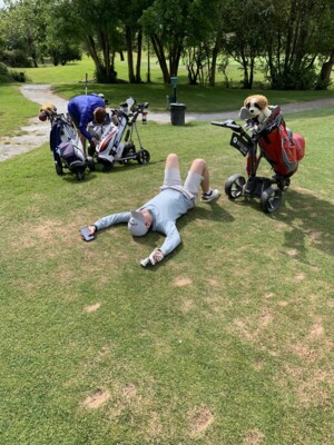 One of the members of the bogeymen is laying on grass. Next to them are golf club caddies.