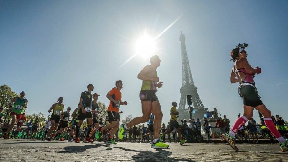 A group of runners are running past the Eiffel Tower.
