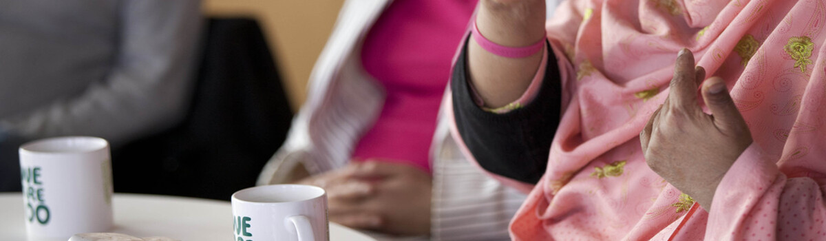 A group of people sitting around a table with mugs of tea.