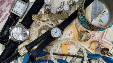 Different items like watches and jewellery are on top of different bank notes.