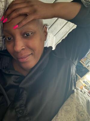 Woman lying down, wearing a black shirt, and resting her hand on her head