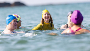 Ellie Rickets is pictured in the middle of a group of swimmers. They are in an open body of water. They are all wearing swimming caps.