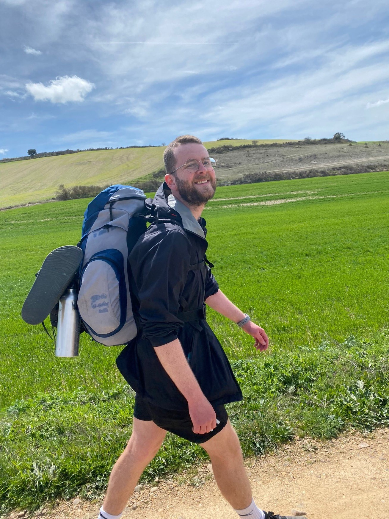 A man carrying a large backpack walks through the countryside.
