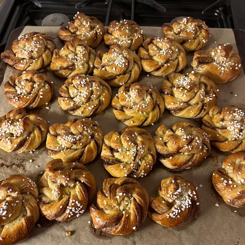 A tray of traditional cinnamon buns on baking parchment paper. 