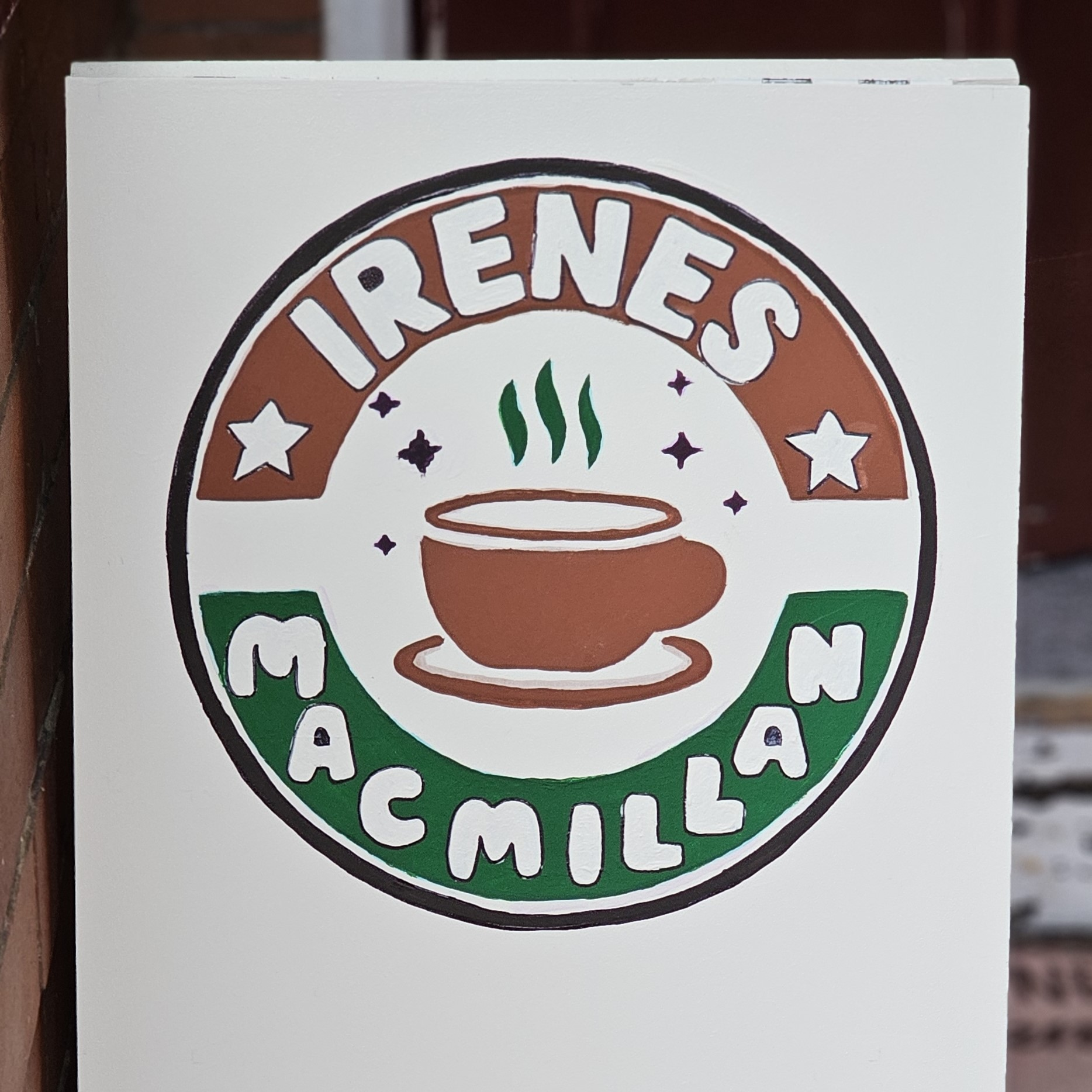 A sign for Irene's Coffee Morning. There is a bespoke logo that says Irenes Macmillan and has a painting of a coffee.