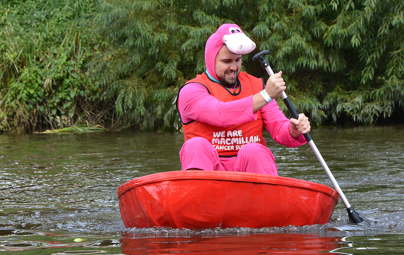 Man in a Dino onesie paddling a coracle